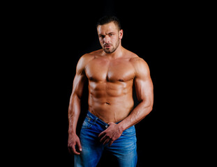 Naklejka premium Muscular sexy guy with naked torso. Portrait of strong healthy handsome athletic man fitness model posing on black. Sexy man. Seductive face of a sexy man. Sexy naked torso, six pack abs.