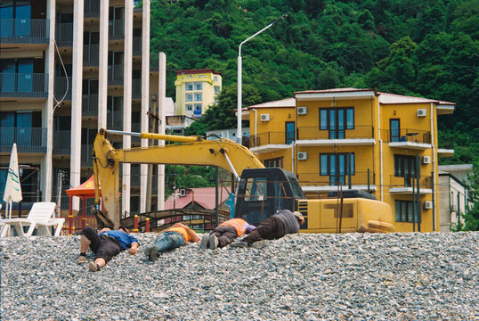 workers and builders rest near construction equipment