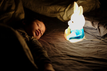 Young boy falls asleep next to bunny night light