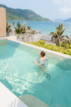 Young plus-size girl swimming in ainfinity pool with in private resort