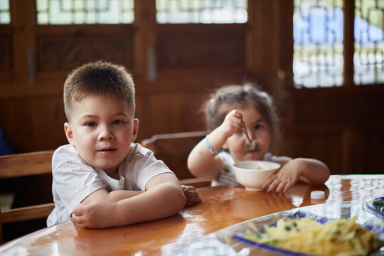 Young Multiracial Asian Boy Sitting At A Table With His Sister.