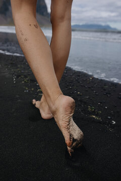 Vertical photo of woman's feet Walking On the black Beach in Iceland