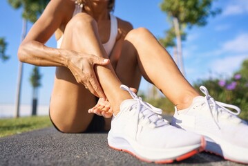 runner with ankle injury holds foot to reduce pain. running problem for athlete training outdoors....