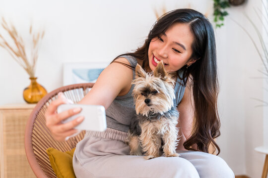 Woman taking a selfie with her dog at home.