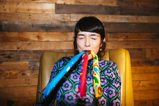 Woman blowing colorful noisemakers during party