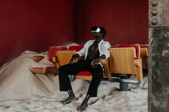 Black man in VR headset in studio with sand