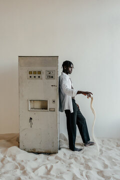 Black man pouring sand near old vending water machine