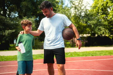 Obraz premium Father and son connect through sports activities, play basketball and enjoy a sunny day