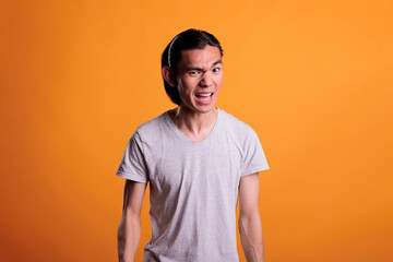Angry young asian man with furious facial expression, showing negative emotions. Irritated person...