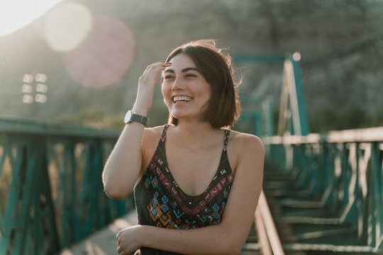 Smiling woman standing outdoors on a railway bridge.