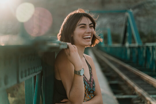 Smiling woman standing outdoors on a railway bridge.