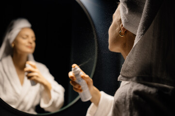 Female spraying lotion near mirror
