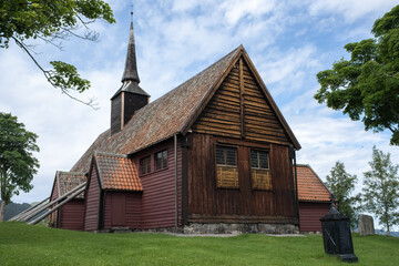 Fototapeta na wymiar Kvernes, Norway - July 03, 2022: Kvernes Stave Church is a former parish church of the Church of Norway in Averoy Municipality in More og Romsdal county. Cloudy summer day. Selective focus