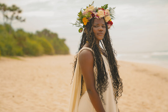 Black woman at the beach with a flower crown facing to the camera