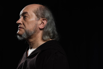 Obraz premium profile portrait of senior monk with grey hair and beard looking away isolated on black.