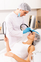 Professional beautician performing needle-free mesotherapy to revitalize and tighten female client...