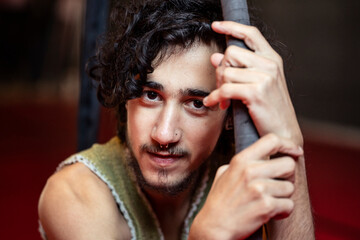 Self assured male performer leaning on hoop on stage