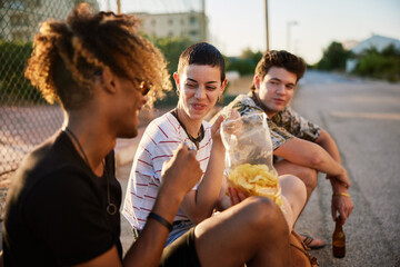 Merry friends eating chips on street