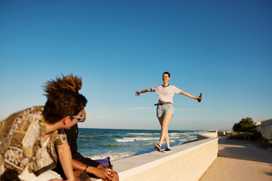 Female with beer walking on border towards friends