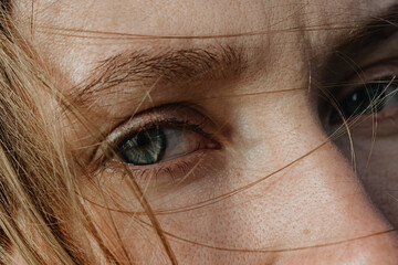 Close Up woman's portrait with grey eyes and blonde hair covered face 