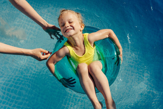 Girl chilling on tube near mother in pool