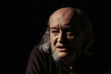 portrait of senior pensive priest thinking isolated on black.