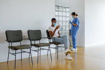 Patient using smartphone while sitting in a waiting room.
