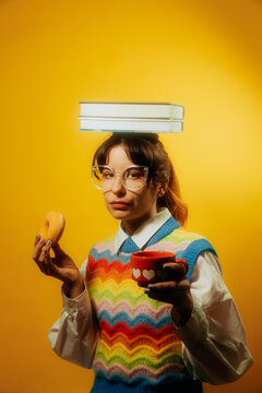 NERDY WOMAN HOLDING TWO BOOKS ON HER HEAD WHILE DRINKING COFFEE 