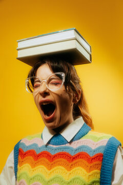 NERDY WOMAN YAWNS WHILE HOLDING TWO BOOKS ON HER HEAD