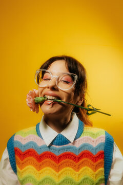 FUN PORTRAIT OF SMILING NERDY WOMAN WITH A CARNATION BETWEEN HER LIPS