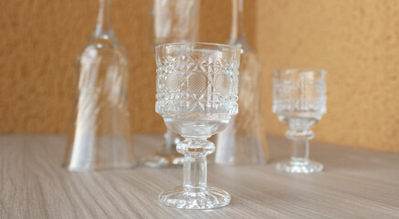 Set of empty crystal cups and goblets for wine and other drinks featuring a small adorned goblet in closeup. Glassware for dining, bar, home decor.