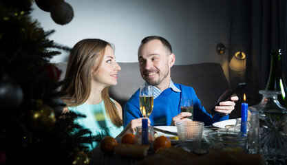 Portrait of loving couple watching tv during celebration of Christmas at table at home