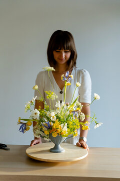 woman florist posing near self-made ikebana bouquet 