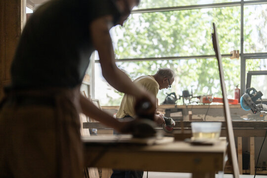 Two men using grinder machine removes old paint from furniture