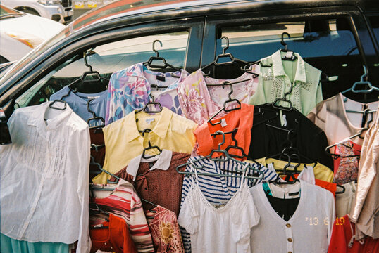 Lots of clothes hanging on the car for sale at the local market