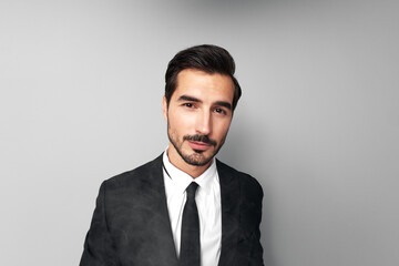 Man businessman in suit smokes e-cigarette and blows steam from his mouth, smoking and health stress in gray background close-up of face at wide camera angle