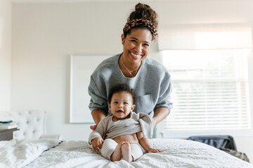 A mother dressing her newborn baby in a cute outfit