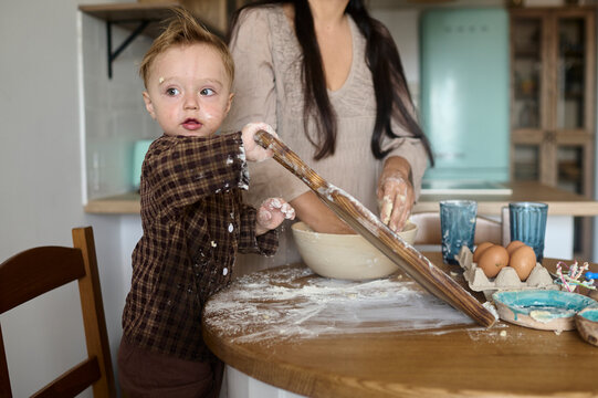 a little son is cooking with his mother in the kitchen