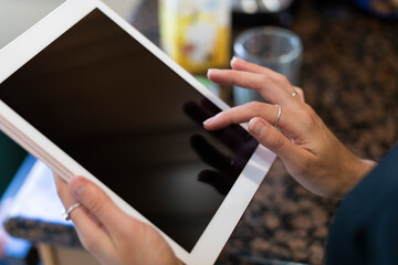 Two hands hold an ipad in the kitchen
