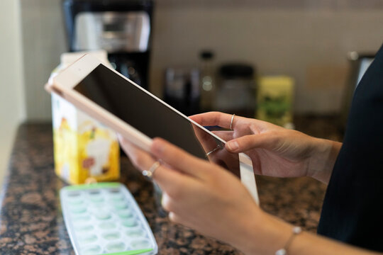 Two Hands Hold An Ipad In The Kitchen