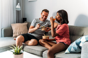Content diverse couple eating poke bowls at home