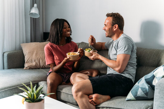 Content diverse couple eating poke bowls at home