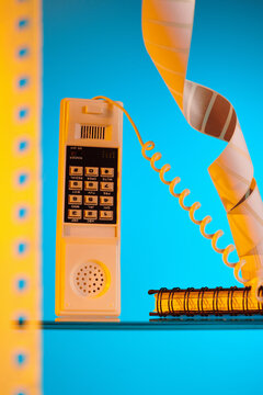 Orange telephone with office trifles on a blue background.