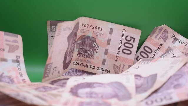 Ca&iacute;da o lluvia de billetes de 500 pesos mexicanos sobre un fondo verde 