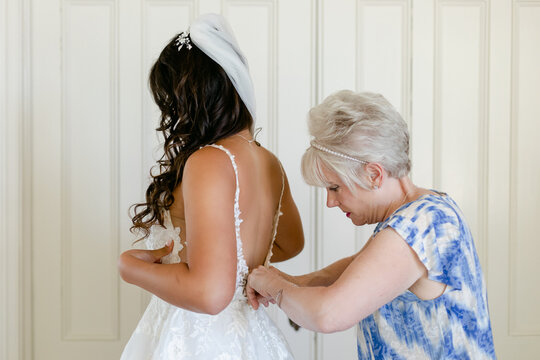 A Bride's Mother Helps Button up her Wedding Dress