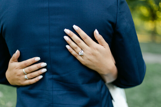 Closeup of Bride's Hands on Groom's Suit