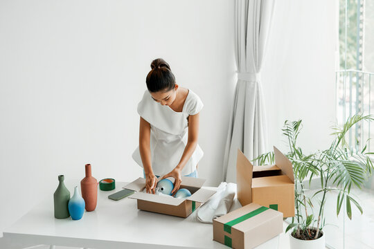 woman putting handmade jug or vase into the box