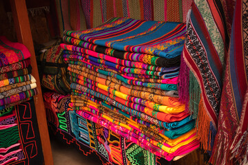 colorful stand of handmade blankets and tablecloths at the Pisac craft market, Cusco, Peru, South...