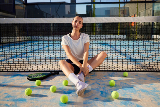 Padel player sitting on sports ground - Powered by Adobe