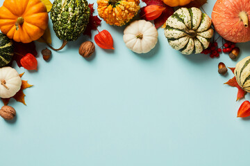 Autumn Thanksgiving background. Pumpkins, acorns, walnuts, physalis and maple leaves on pastel blue table top view. - obrazy, fototapety, plakaty